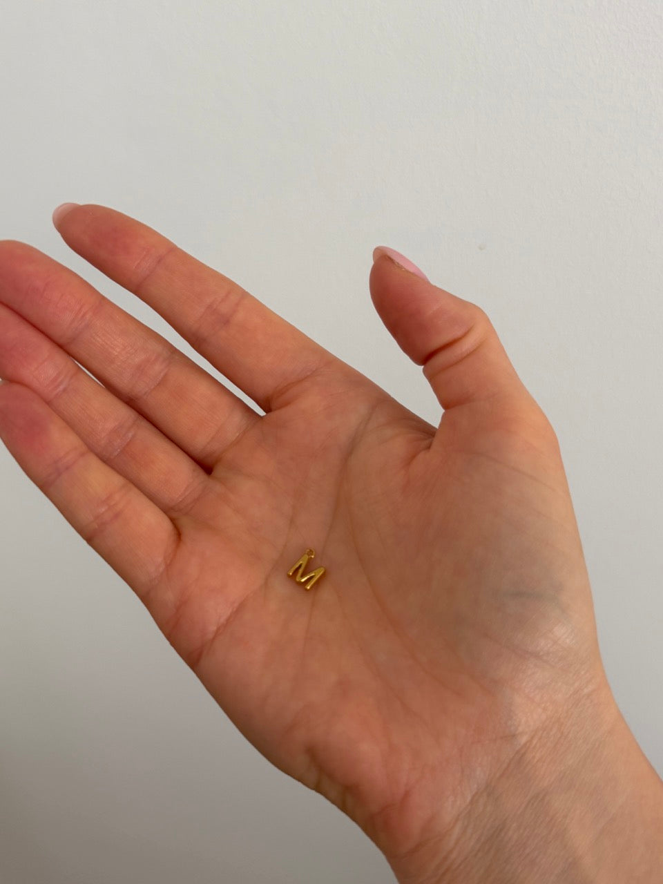 Größenvergleich: Buchstabe M Anhänger auf der Hand