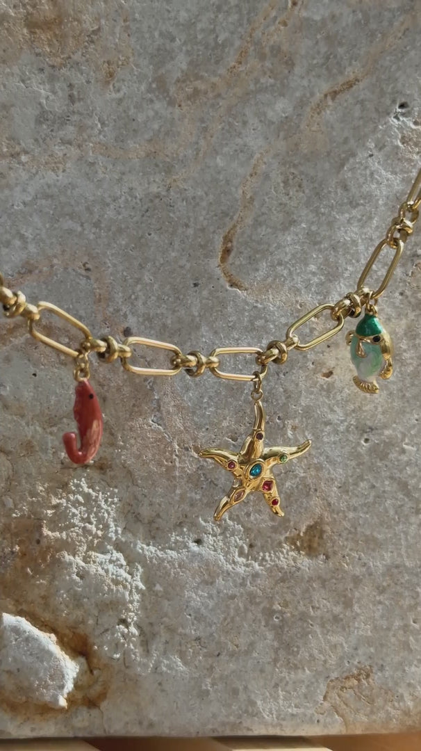 Detailaufnahme von einer massiven Goldkette mit maritimen Anhaengern