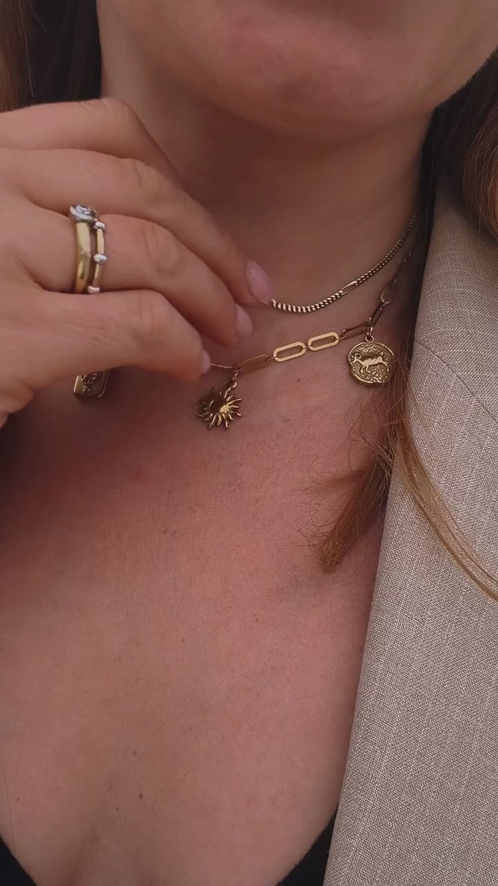 Dekollette von Frau st zu sehen, sie zeigt ihre Goldkette mit drei goldenen Anhaengern